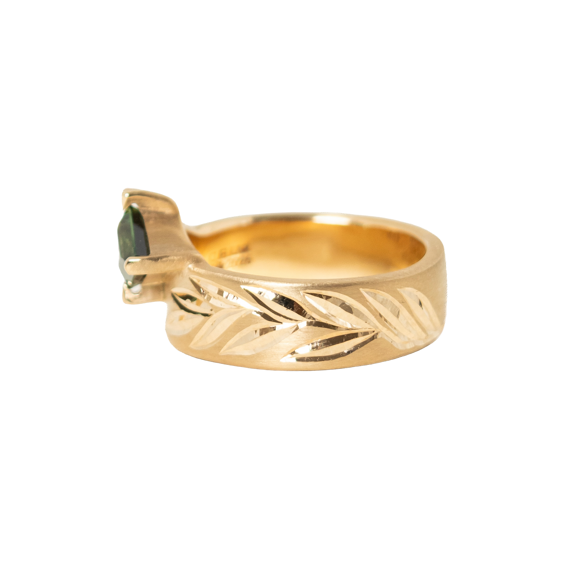 A 14k gold ring featuring a hexagon dark green sapphire in a prong eagle setting, with an hand engraved leaf pattern on the band, shown against a plain white background.