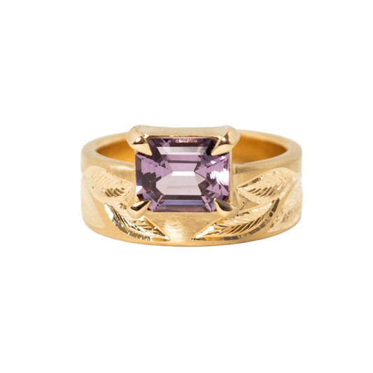 A 14k yellow gold ring featuring a rectangular emerald-cut light purple sapphire set against a plain white background.